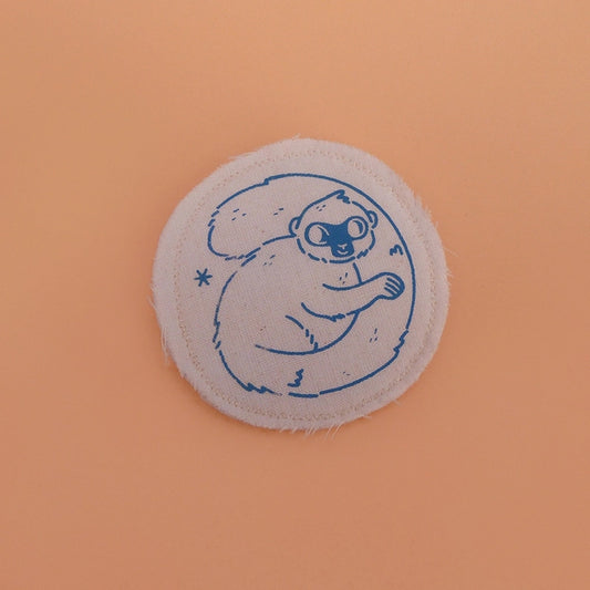 Broche mignonne fabriquée à la main avec des chutes de tissus. Dessin de lémurien à front blanc.