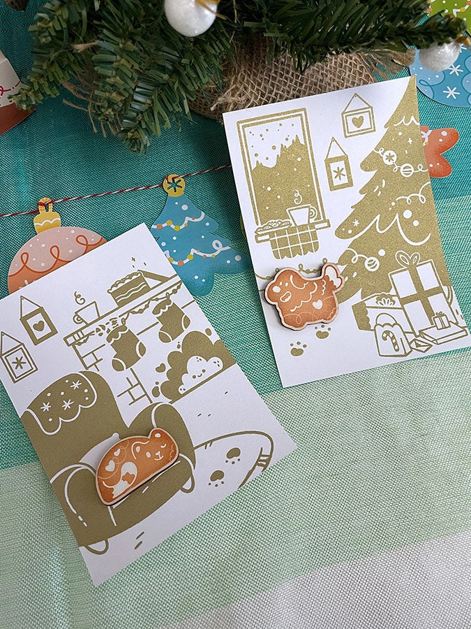 Carte de vœux sérigraphiée artisanalement. Décor cosy de fêtes. Cheminée, biscuits, chocolat chaud, sapin et cadeaux.