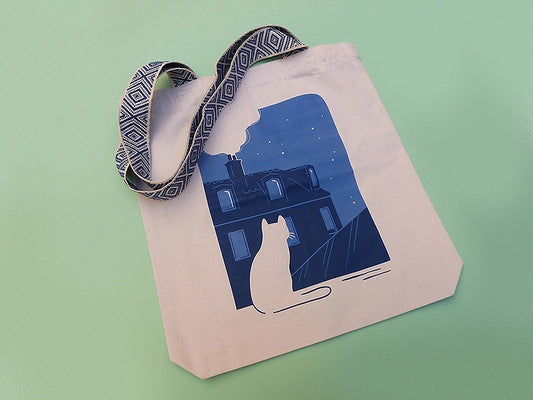 Grand totebag fabriqué en matières recyclées. Impression française. Illustration d'un chat regardant les toits de Paris la nuit.