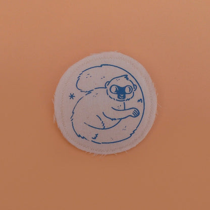 Broche mignonne fabriquée à la main avec des chutes de tissus. Dessin de lémurien à front blanc.