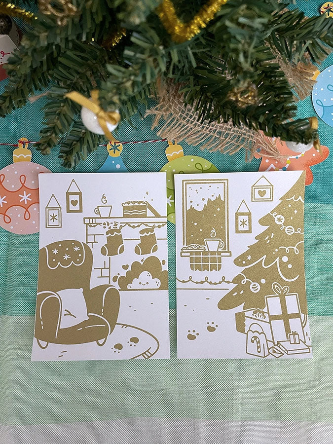 Carte de vœux sérigraphiée artisanalement. Décor cosy de fêtes. Cheminée, biscuits, chocolat chaud, sapin et cadeaux.