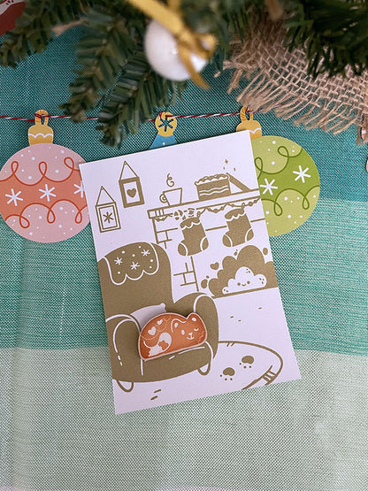 Carte de vœux sérigraphiée artisanalement. Décor cosy de fêtes. Cheminée, biscuits, chocolat chaud, sapin et cadeaux.