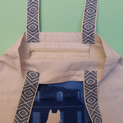 Grand totebag fabriqué en matières recyclées. Poche zippée à l'intérieur. Anses larges et confortables. Impression française. Illustration d'un chat regardant les toits de Paris la nuit.