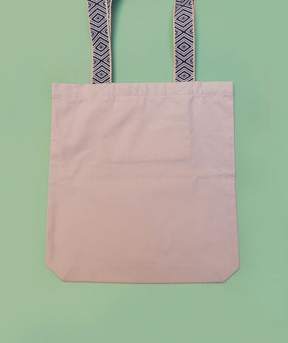 Grand totebag fabriqué en matières recyclées. Poche zippée à l'intérieur. Anses larges et confortables. Impression française. Illustration d'un chat regardant les toits de Paris la nuit.